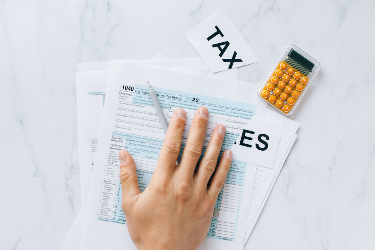 Hand completing an income tax return form with a calculator